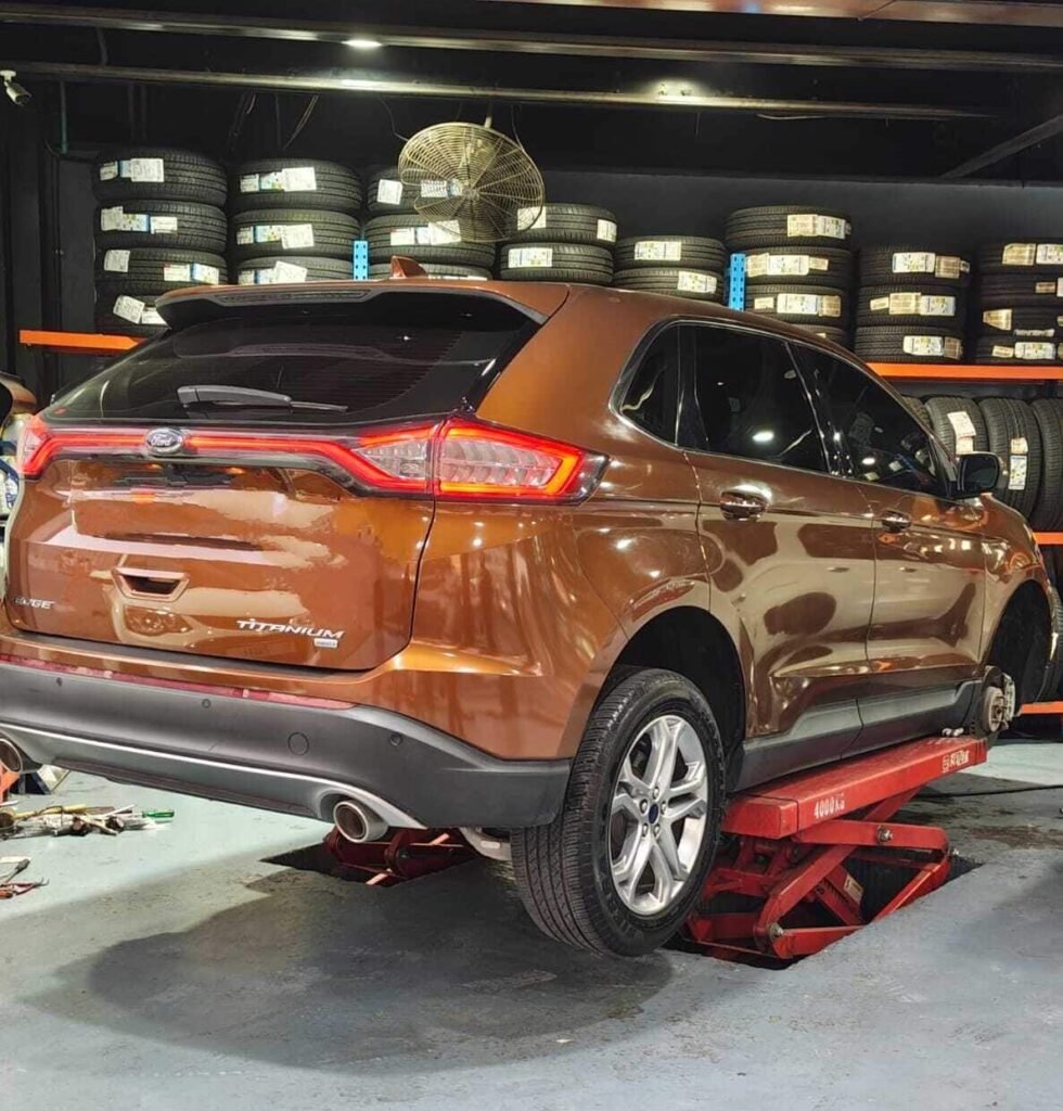 Rusty Orange Car is elevated on a hydraulic lift inside a garage for car service