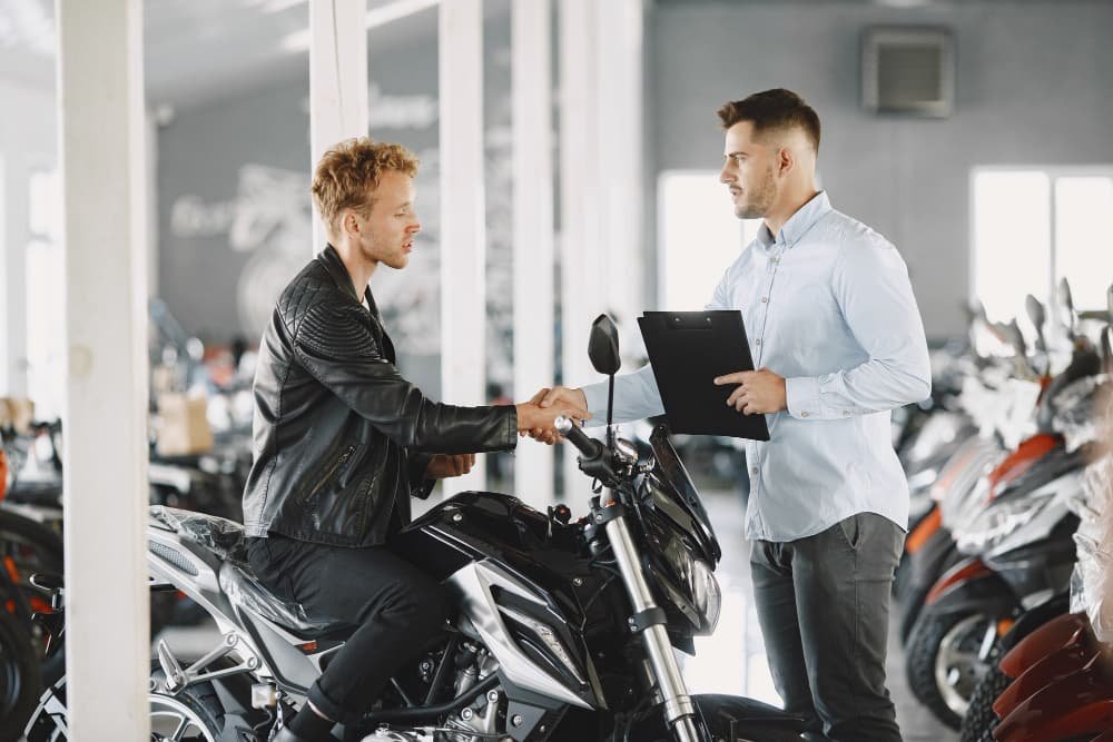 A man holding the papers shaking hands with customer after completing motorcycle export documents.